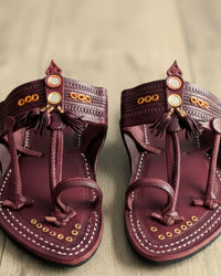 Maharaja in maroon with gold studs and tassels, pair on a teak surface